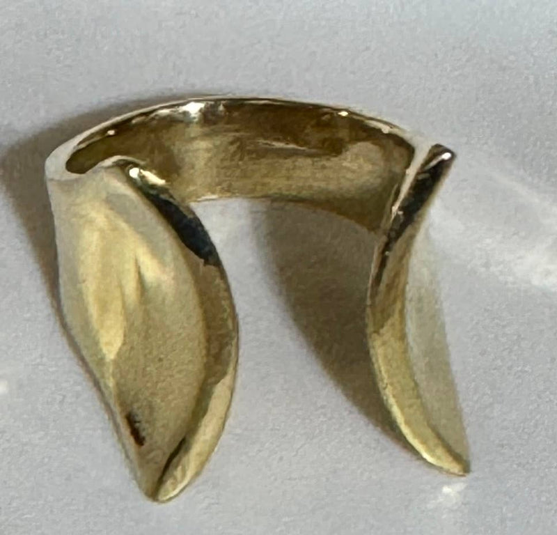 Gold ring with a unique design on a light gray background